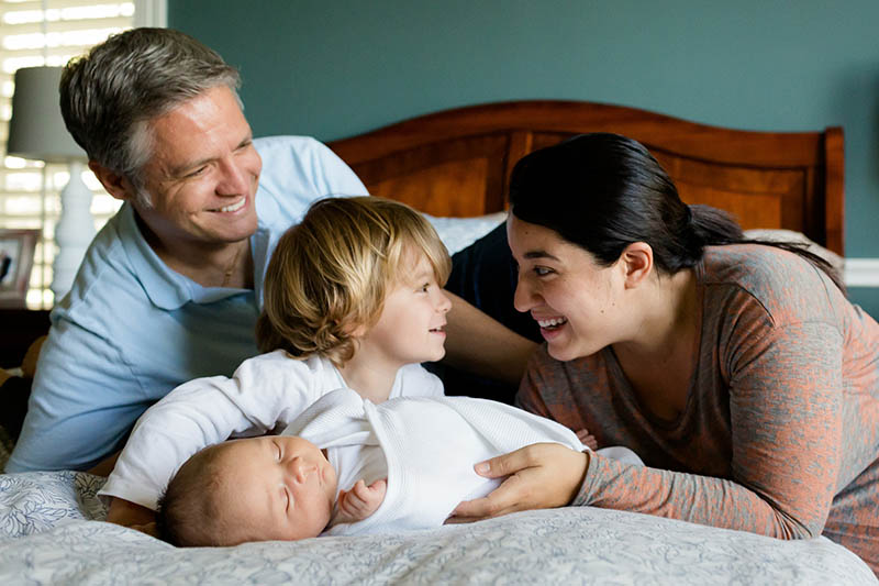photo of couple laying in bed with their two children