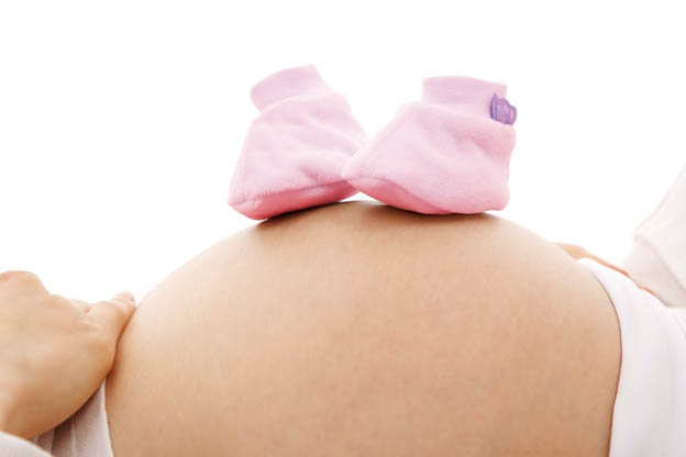photo of a pregnant belly with little newborn boots on top