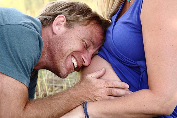 photo of stephanie's husband resting his head on her belly smiling