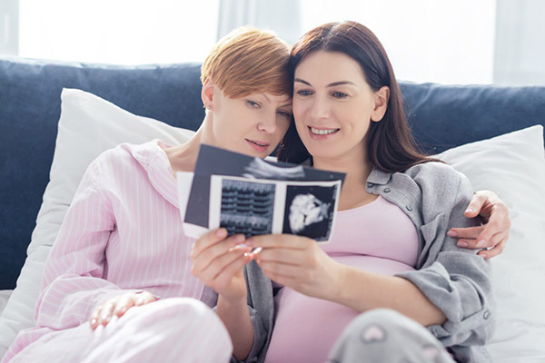 photo of a same sex couple in pajamas looking at a sonogram