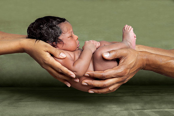 photo of a newborn baby being held by two sets of hands